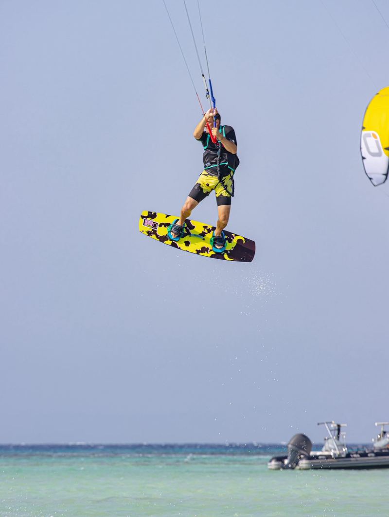 Kiter jumping high above the water, boat in the distance