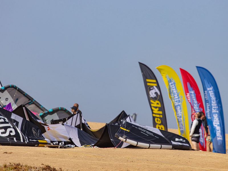 Kites and beach flags lined up on the sand